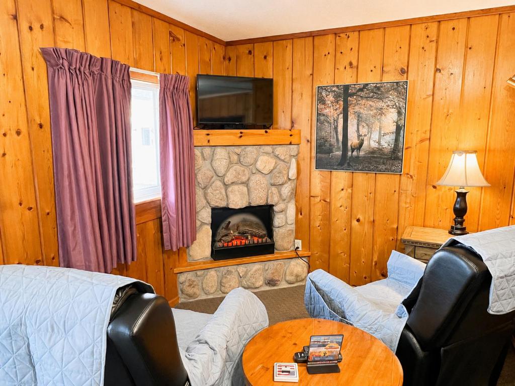 a living room with a fireplace and a tv at Cedars Motel in Saint Ignace
