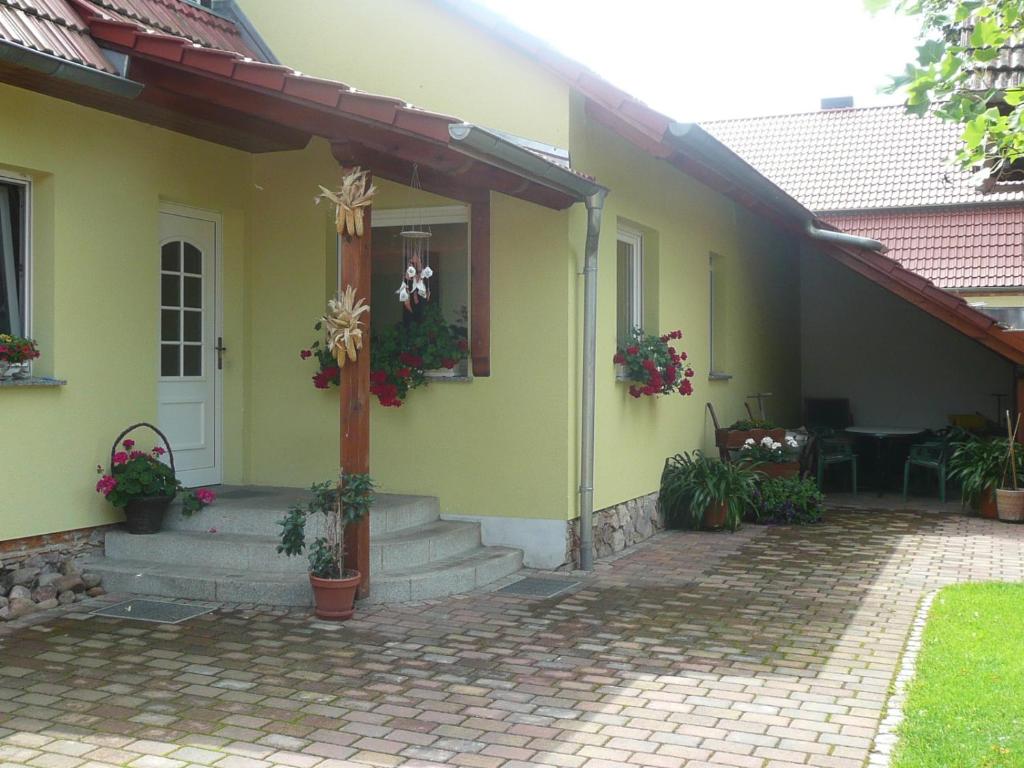 a yellow house with a front porch with potted plants at Landurlaub in Schiebsdorf in Kasel-Golzig