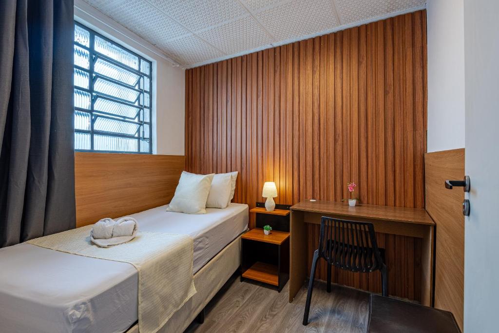 a hotel room with a bed and a desk at Pousada Hostheo liberdade in São Paulo