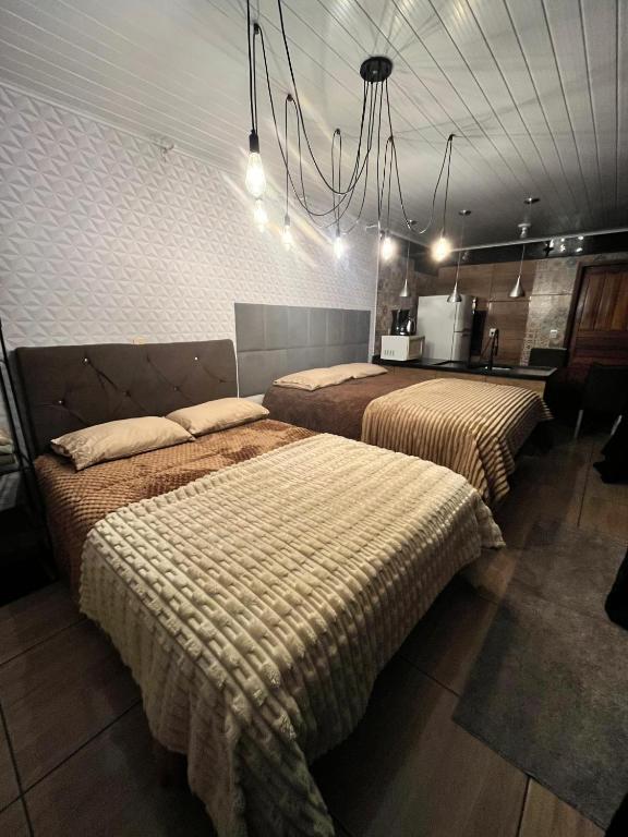 a bedroom with two beds and a chandelier at Quarto Aconchegante N 3 in Rio Negro