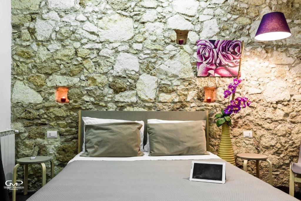 a bed in a room with a stone wall at B&B Siracusa in Syracuse