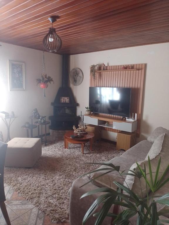 a living room with a couch and a tv at Aconchego da Wal in Campos do Jordão