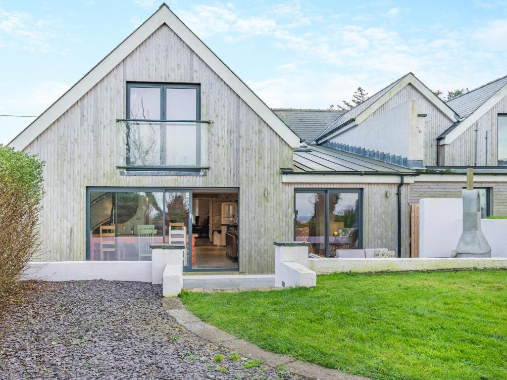 a wooden house with glass windows and a yard at Ty Eufron in St. Davids