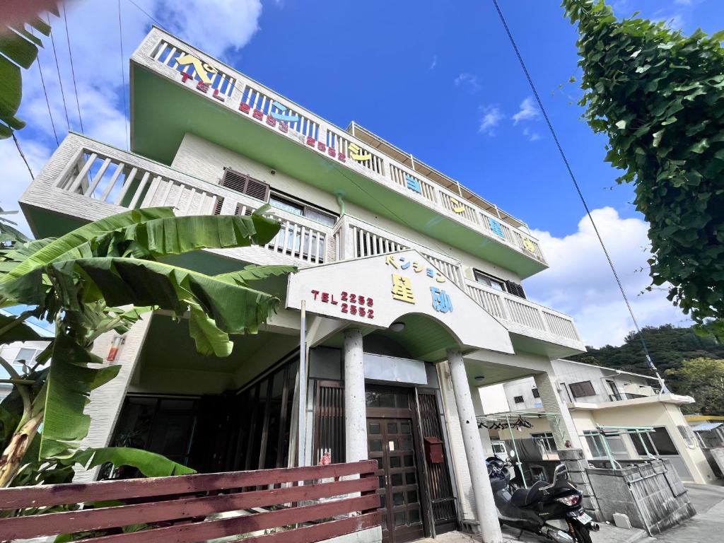 a green and white building with a sign on it at ペンション星砂 in Zamami