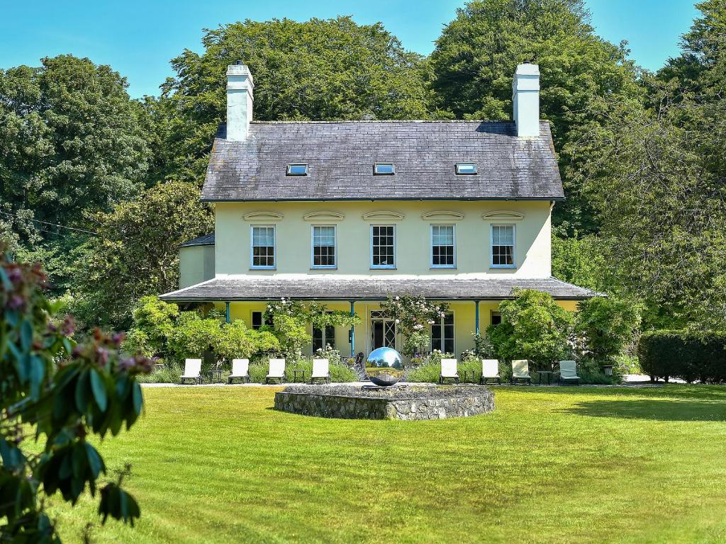 a large white house with a fountain in the yard at Plas Bodegroes in Pwllheli