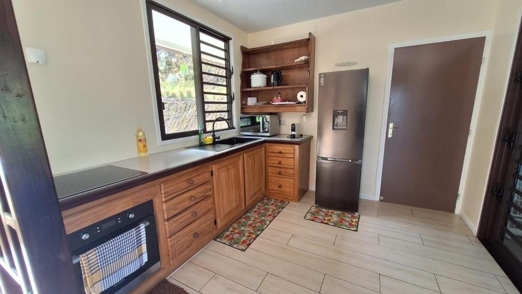 a kitchen with wooden cabinets and a stainless steel refrigerator at Temoe'ani House in Uturoa