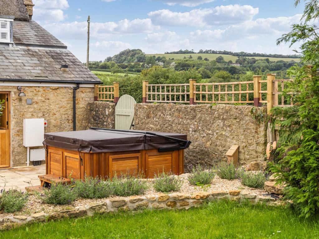 a hot tub in a garden next to a stone wall at Lower Barrowfield Farm in Beaminster