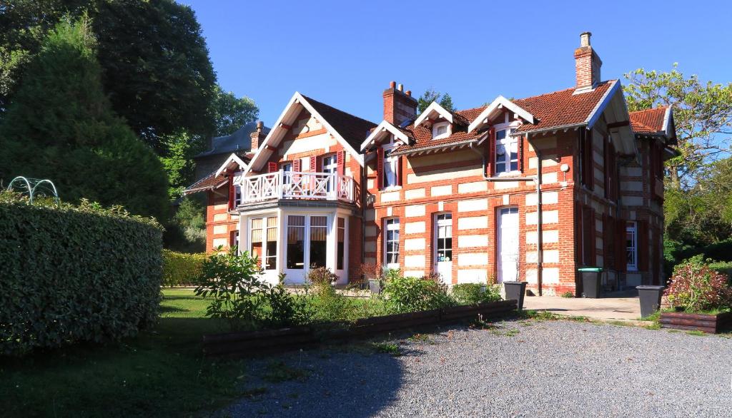 Una gran casa de ladrillo con balcón. en La Villa des Rosiers, en Cricquebœuf