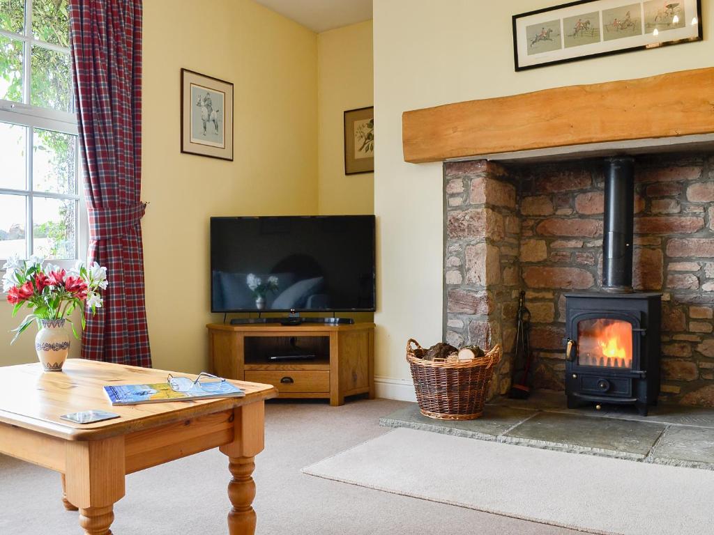 a living room with a fireplace and a television at Osprey Cottage - Uzq in Kirkton of Airlie