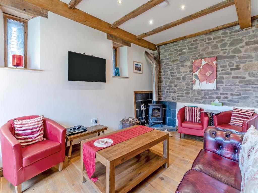 a living room with red furniture and a tv at Wern Farm Barn in Cwm-du