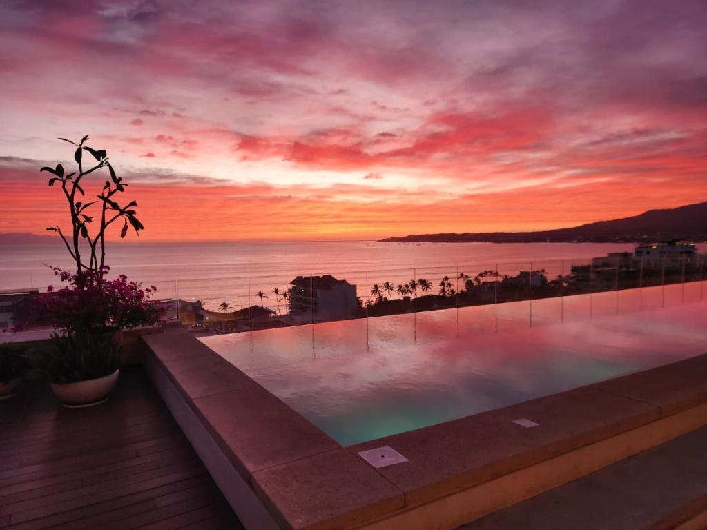 a swimming pool with a sunset in the background at Maralma Bucerias 1 half Blocks from Beach Sleeps 4 in Bucerías