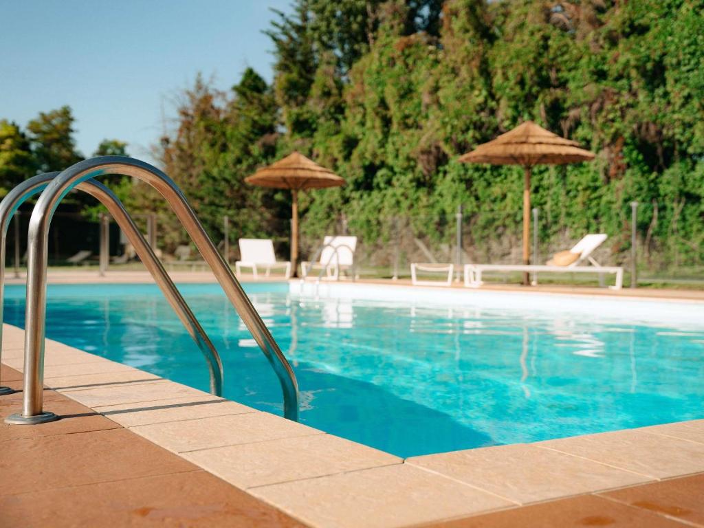 a swimming pool with umbrellas and chairs and a swimming pooliterator at Mercure Valence in Valence