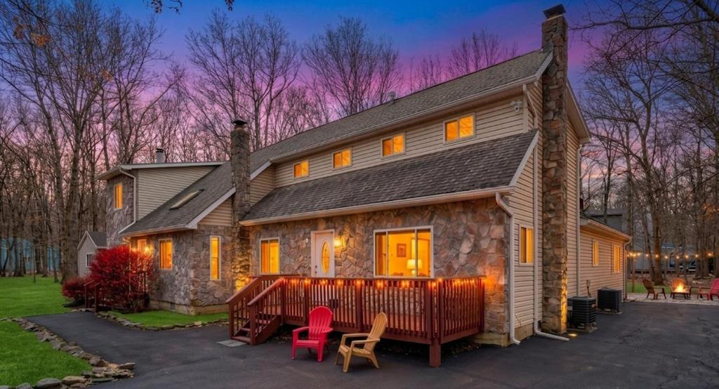 a house with two pink chairs in front of it at 6BR Luxury Mountain Retreat - Hot Tub, Game Room, Lake, Beach, Karaoke, Bar, Poconos in Albrightsville