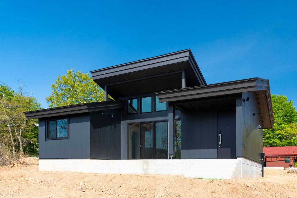 a black house on a hill with trees at Asahi Shizenkan in Asahi-machi