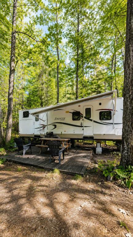 a white rv parked in the woods with a picnic table at 2-bedroom Camper Trailer Cottage #3 in Dillon