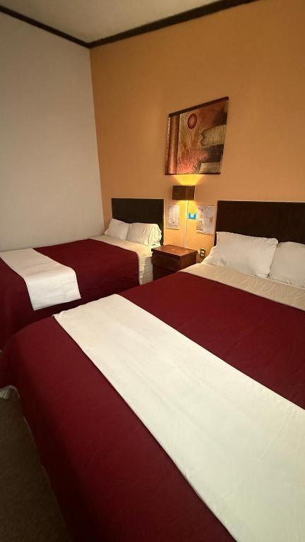 two beds in a hotel room with red and white sheets at Hotel Santa Fe in Chignahuapan