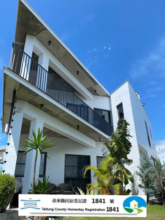 a white building with a balcony and palm trees at 木木宿宿MUMUsusu-stay只接待成年者一無包棟服務 in Taitung City