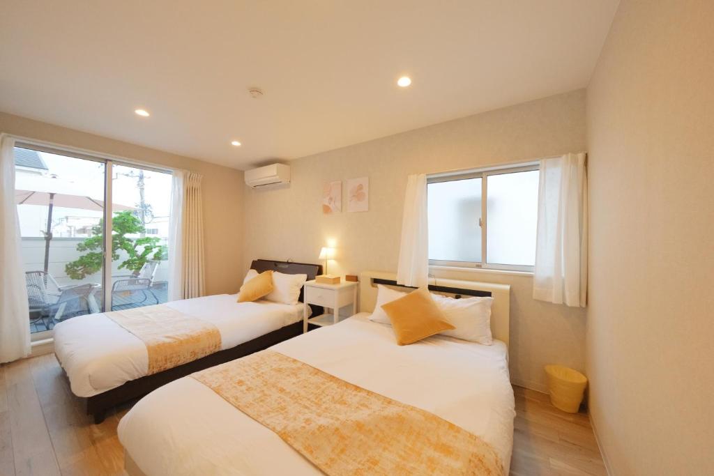 two beds in a room with two windows at 愉楽の宿 一棟貸切Villa in Osaka
