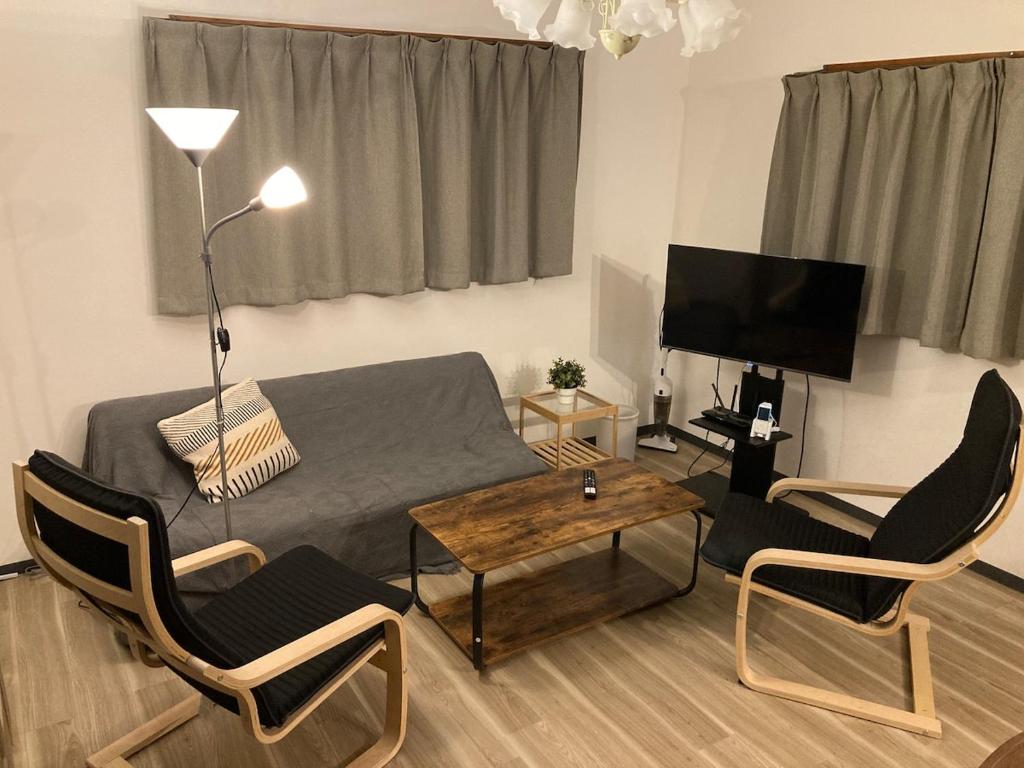 a living room with a couch and chairs and a television at Osaka Convenient Location Entire Private Second Floor in Hirakata