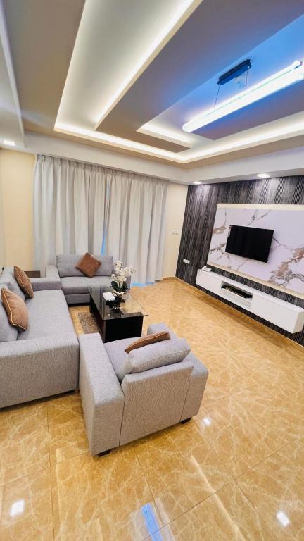 a living room with couches and a flat screen tv at Amber Tower in Al Ghurayfah