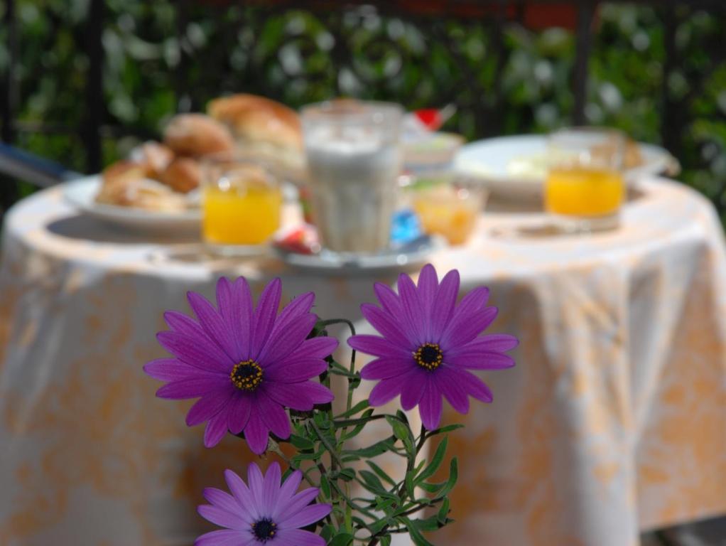 a table with purple flowers in front of a table with food at Hotel del Centro in Palermo