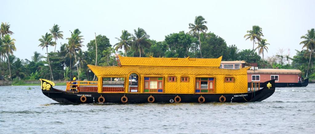 a yellow boat in the water with a house on it at Traditional Houseboat in Alleppey