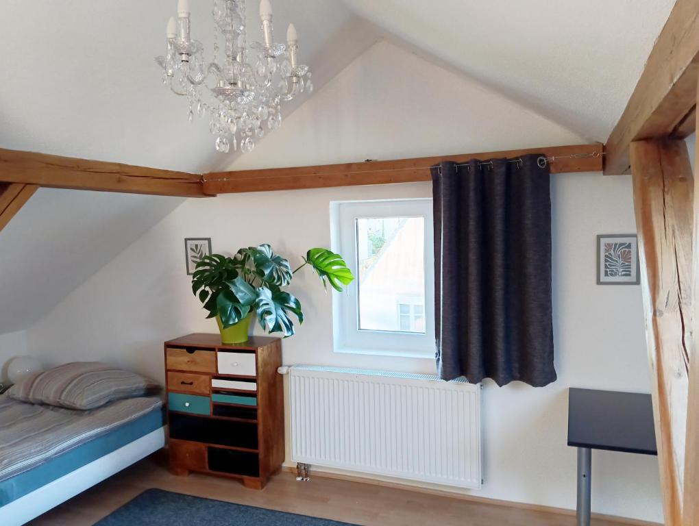 a bedroom with a chandelier and a bed and a window at Gästezimmer in Diedorf