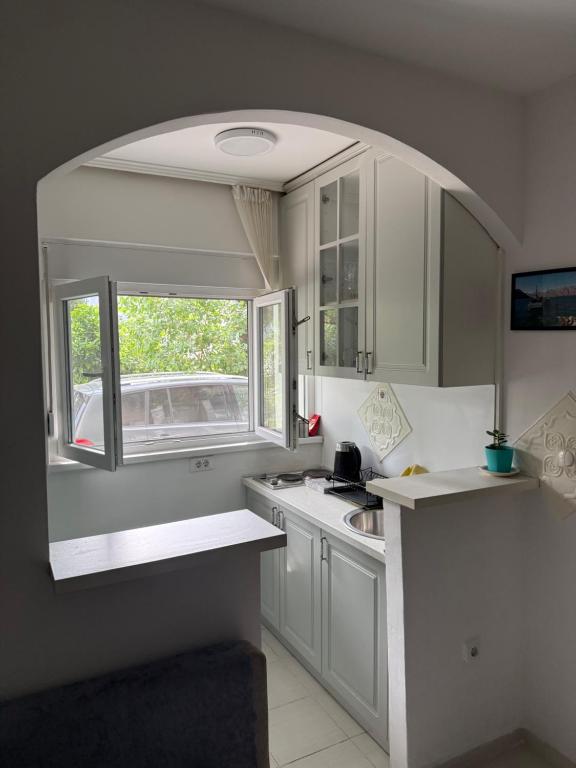 a kitchen with white cabinets and a window at Apartman Dunjićeva in Kotor