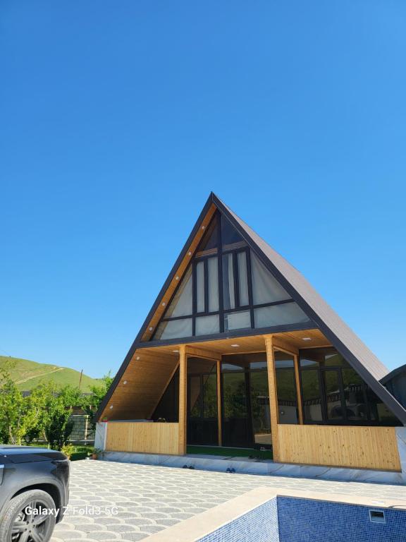 a house with a gambrel roof with a car parked in front at Shabran Pearl A-Frame in Surra
