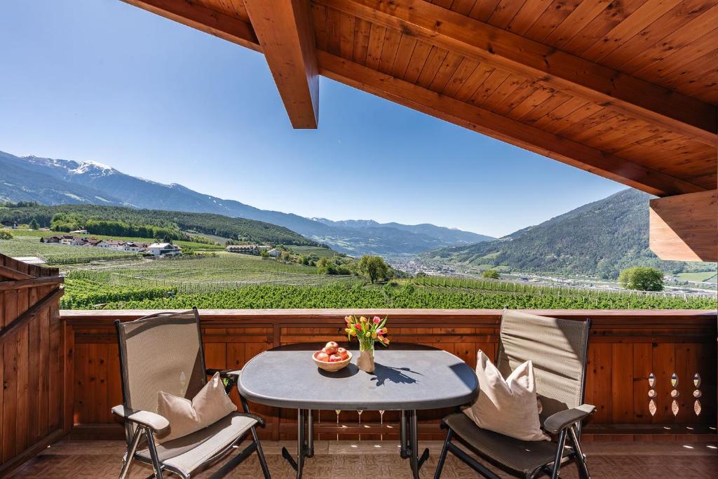 a table and chairs on a balcony with a view of a vineyard at Tirolerhof - panoramic apartments in Natz-Schabs