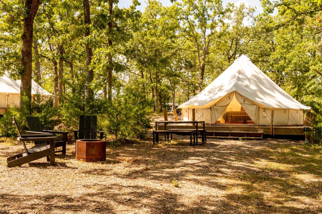 a white tent in the woods with a picnic table at Chic Glamping Tent with Firepit in Branson