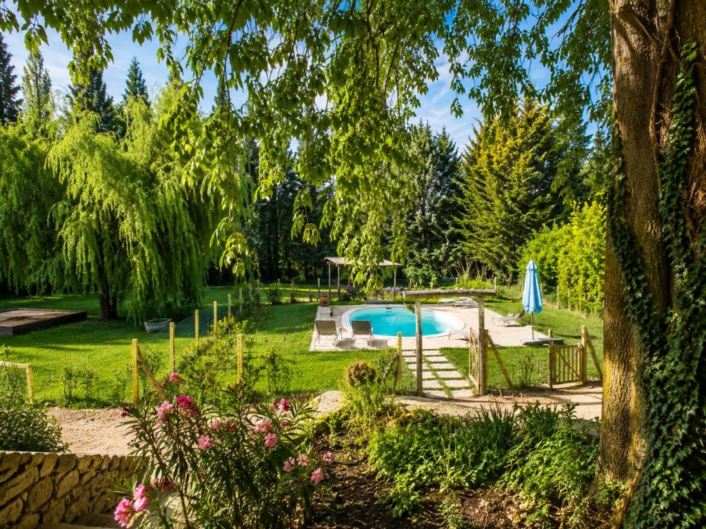 a garden with a swimming pool and trees at Gîte Moulin de l'Anet in Goult