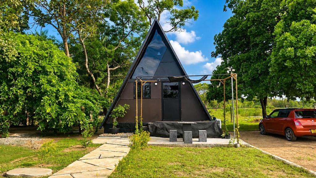 a black triangular building with a window in a park at Ora sigiriya Cabana in Sigiriya