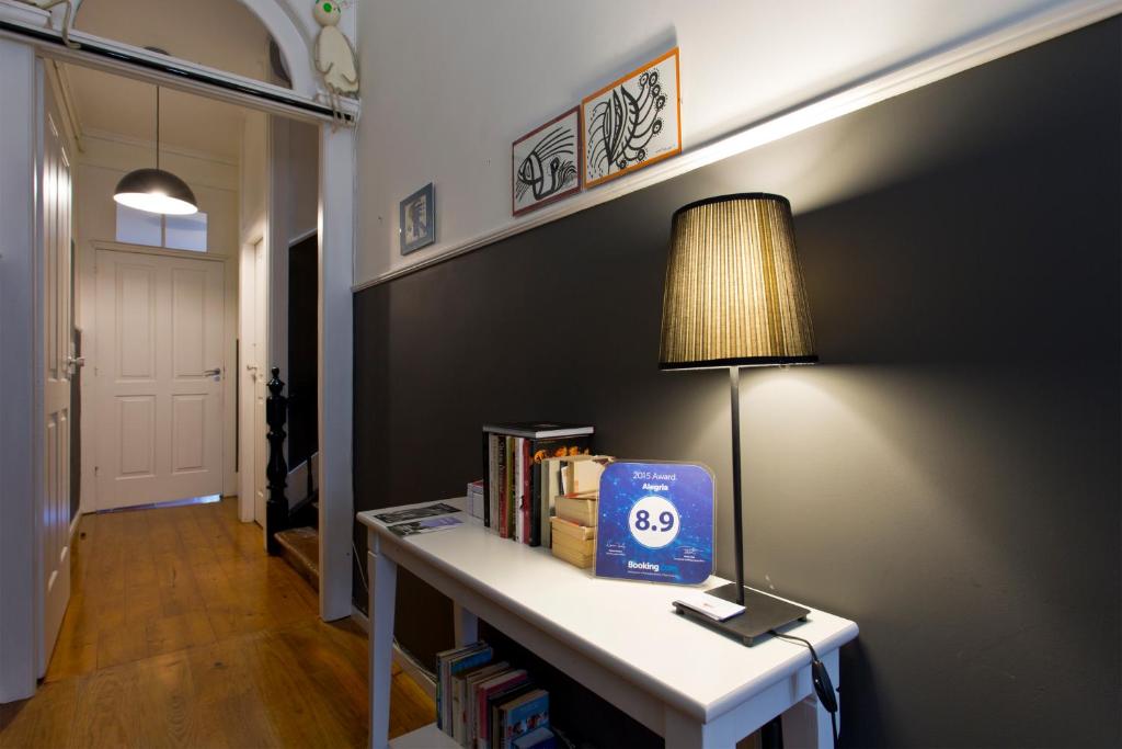 a room with a table with books and a lamp at Hostel Alegria in Porto