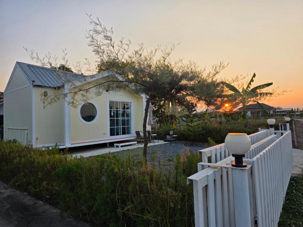 a small white house with a white fence at Wind in the Wild Khao Yai in Ban Khlong Yang