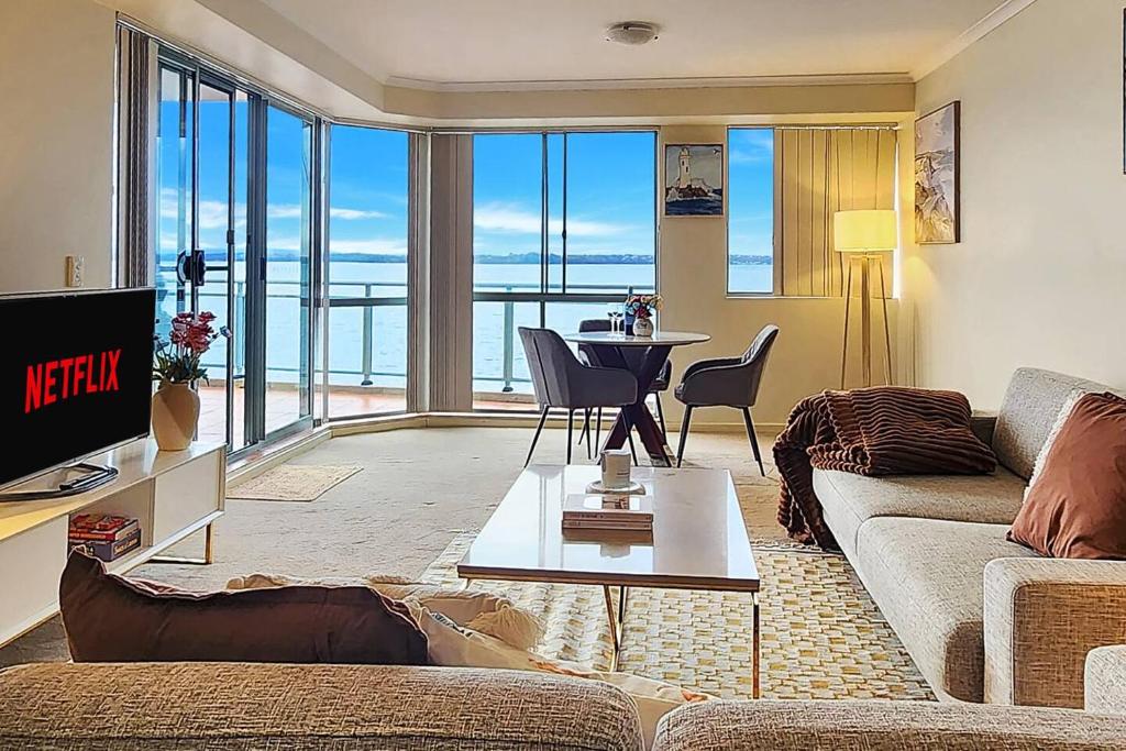 a living room with a couch and a table at Toukley Waterfront Apartment with Balcony - Outdoor Pool - Secure Parking - Wi-Fi - By HappyHosts in Toukley