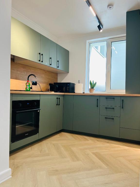 an empty kitchen with green cabinets and a window at Premium Apartment Turda in Turda