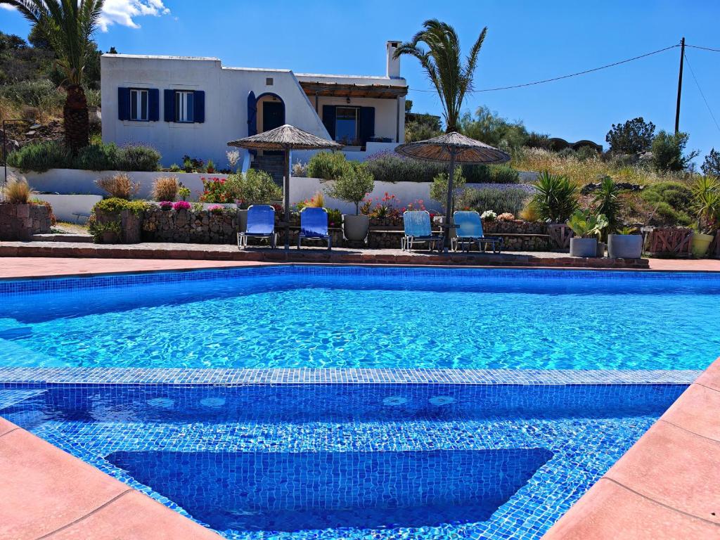 a swimming pool with chairs and a house in the background at Oneiro glico in Agia Marina Aegina