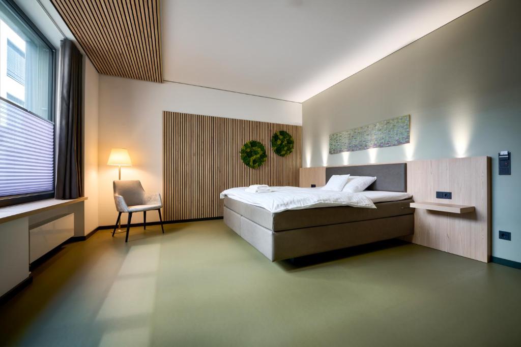 ein Schlafzimmer mit einem Bett, einem Stuhl und einem Fenster in der Unterkunft Hotel Vivendi in Paderborn