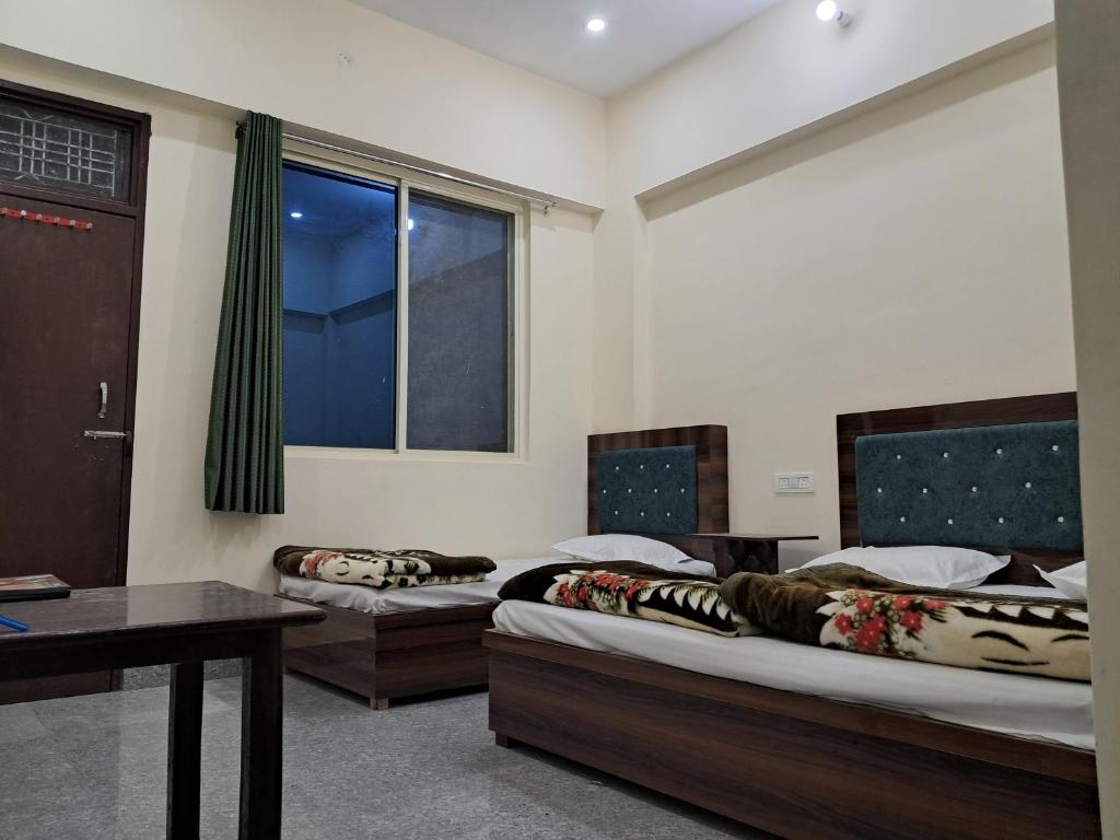 a room with two beds and a table and a window at Krishna palace in Pīpalkoti