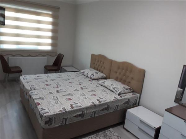 a bedroom with a bed with two chairs and a window at moonlight apart otel in Erzincan