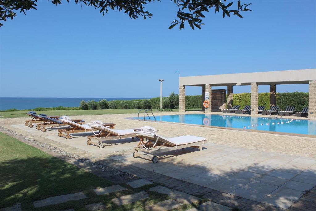 una fila de tumbonas junto a una piscina en Villa Lefka, en Kastrosikia