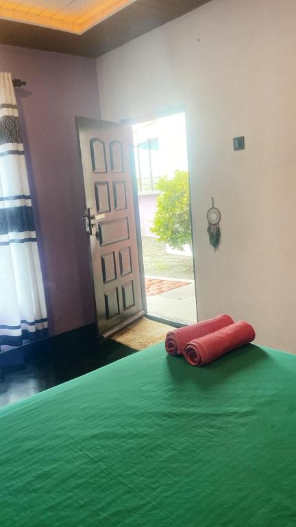 a red towel laying on a bed in front of a door at Anya's Loft - Sky Stay in Mirissa