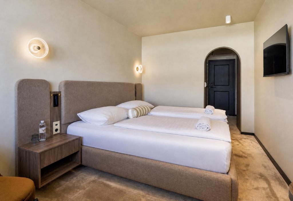 a bedroom with a large white bed and a television at Motel Reich in Velenje