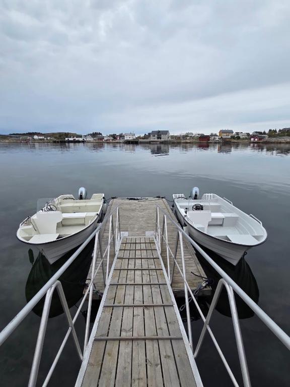 two boats are docked at a dock on the water at Fiskehuset Havnes in Averoy