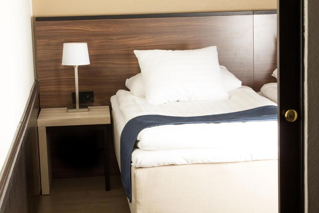 a bedroom with two beds and a table with a lamp at Hotel Oscar in Varkaus