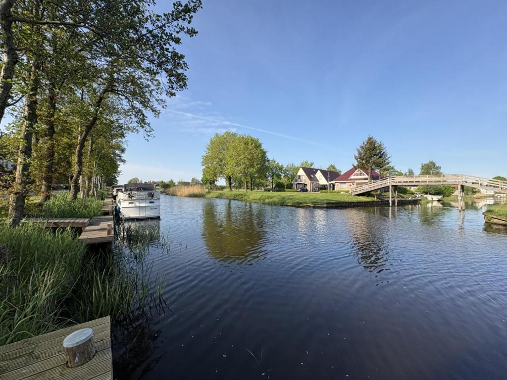 a boat is docked on a river with a bridge at B&B Wetterwille in Opeinde