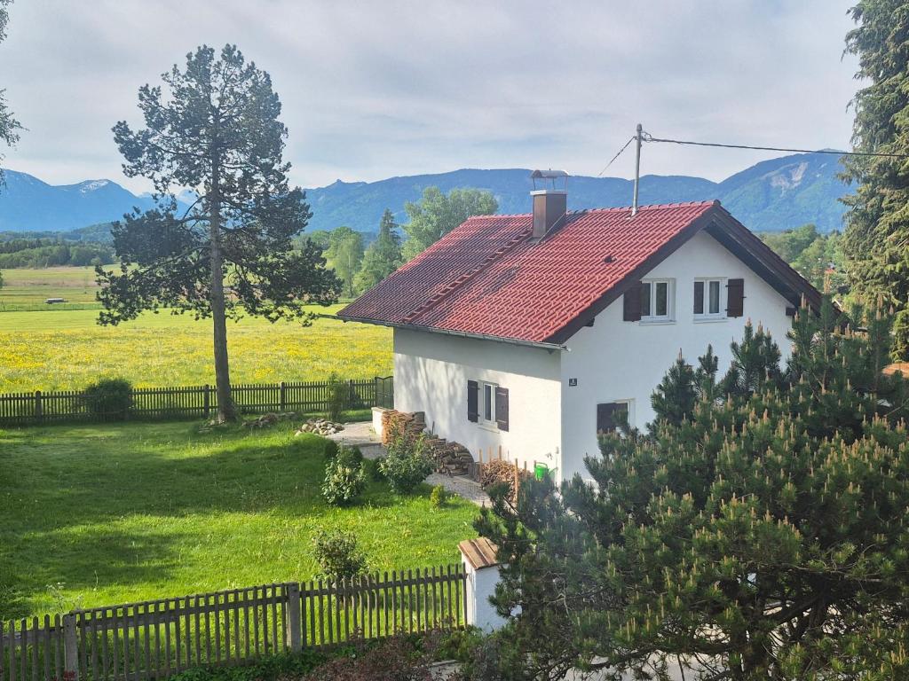 a white house with a red roof and a fence at The Staffelsee Lodge in Uffing