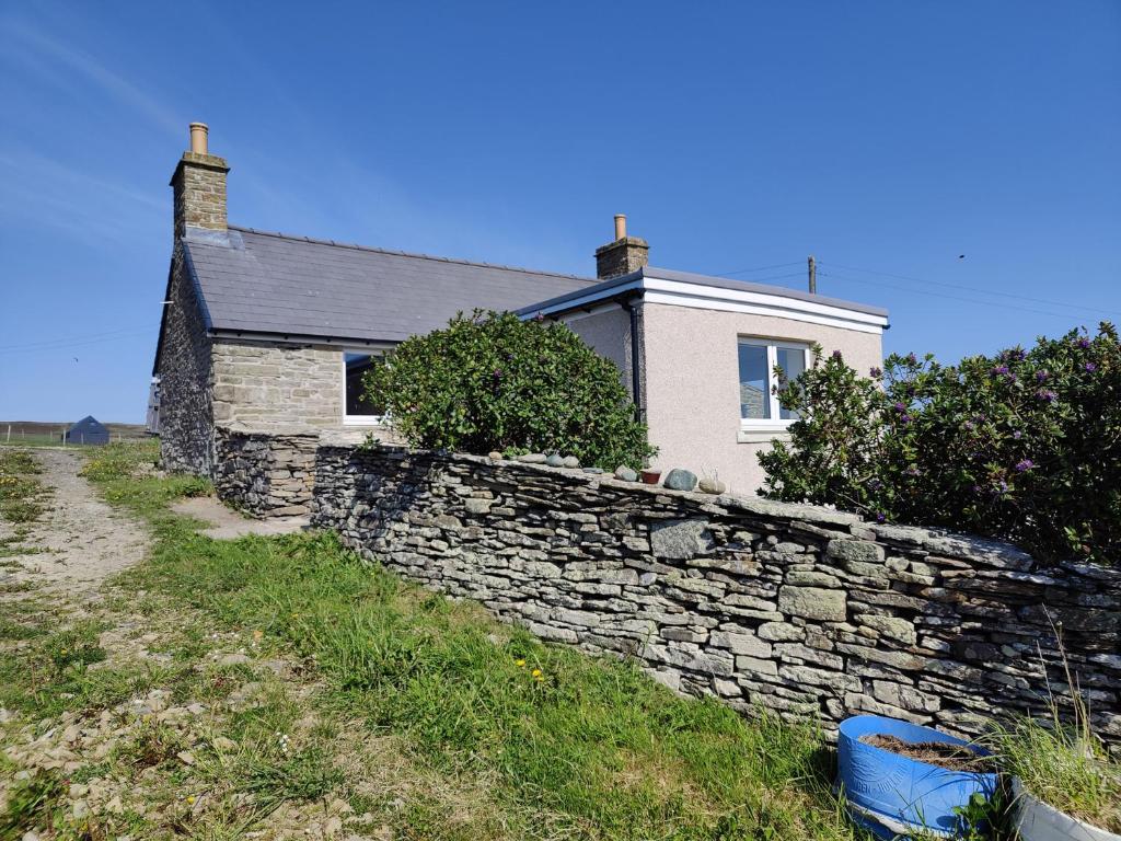 a stone wall in front of a house at Lower Cottage in Orkney