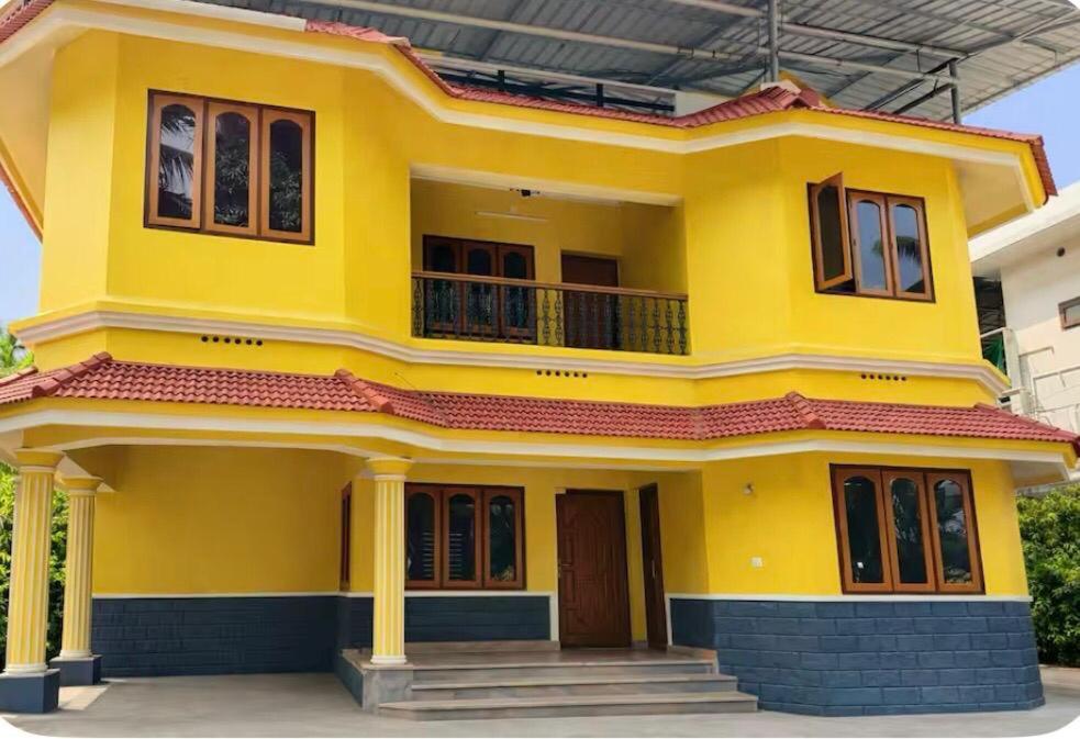 a yellow house with a balcony in front of it at Kandass Homestay in Trichūr